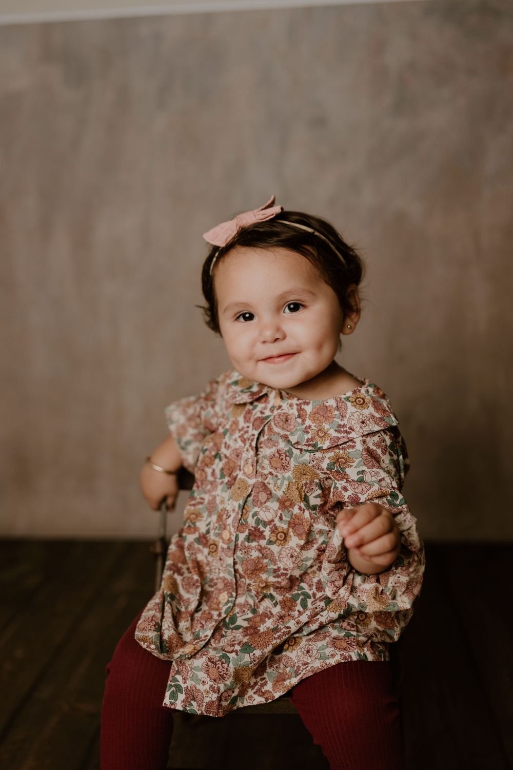 Studio portrait of toddler in floral dress and headband.