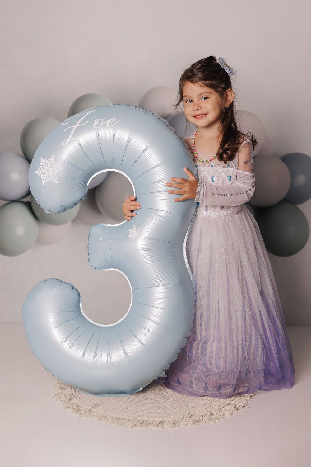 Celebration photo with large silver number 3 balloon and flowing purple princess dress.