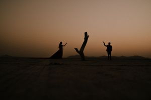 Playful silhouettes against a sunset sky create dynamic poses in a desert landscape.