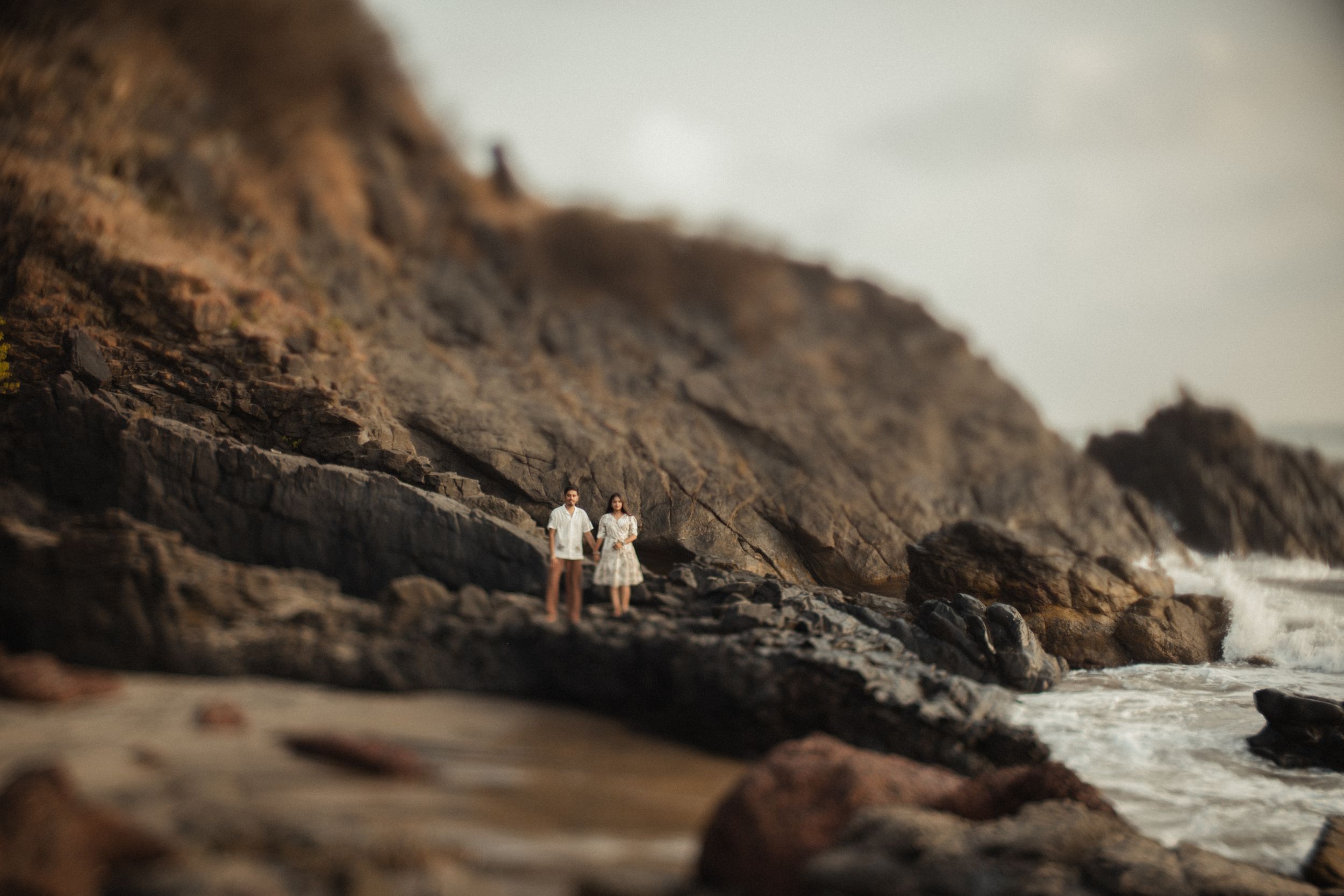 Intimate seaside portrait on rocky cliffs overlooking dramatic coastal waters.
