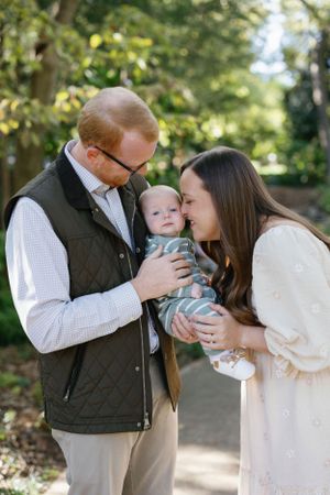 A tender family moment outdoors as parents share an intimate moment with their baby.