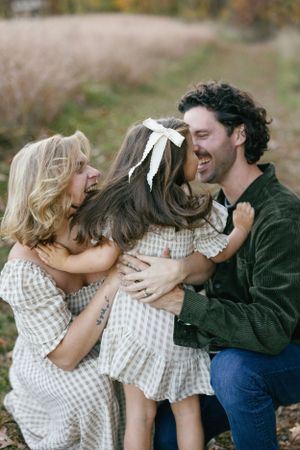 Playful family moment filled with laughter and embraces on an autumn day.