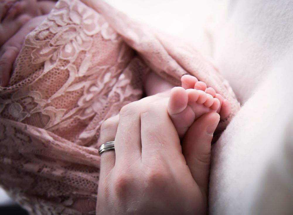 Image of mother holding her babies feet in her hands.