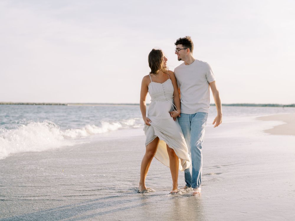 A couple shares a playful moment while walking along the shoreline.