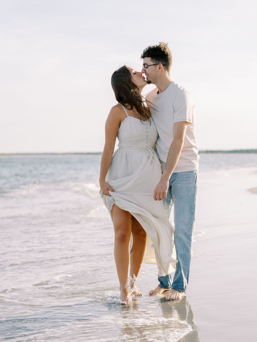 A romantic beach moment with the wind blowing a white dress against the ocean backdrop.