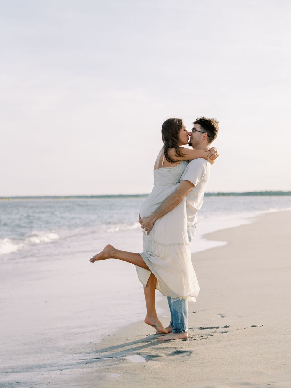 A joyful embrace on the beach with waves rolling in the background.
