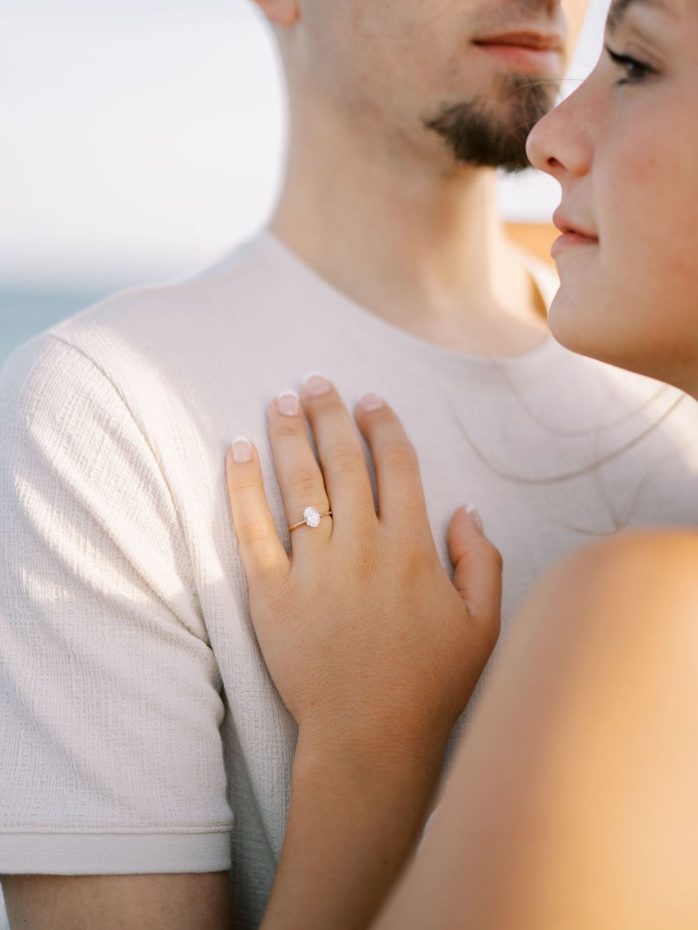 Intimate close-up shot showing engagement ring and tender moment.