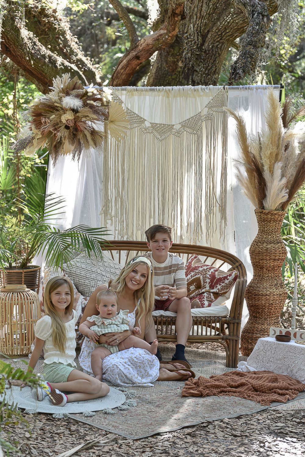 An outdoor family portrait setup with macrame backdrop and bohemian decor elements.