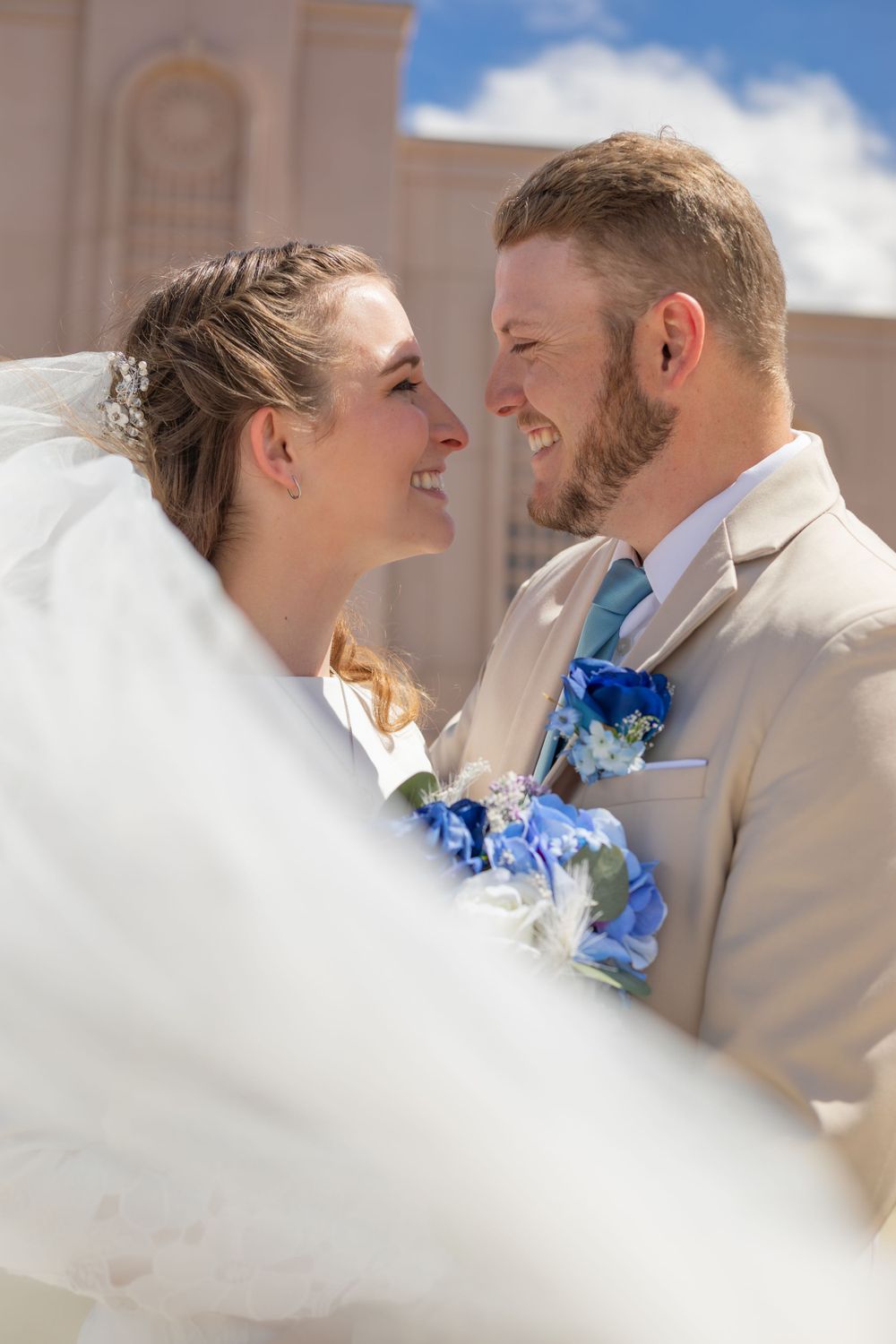 Romantic wedding couple shares intimate moment with blue floral bouquet.