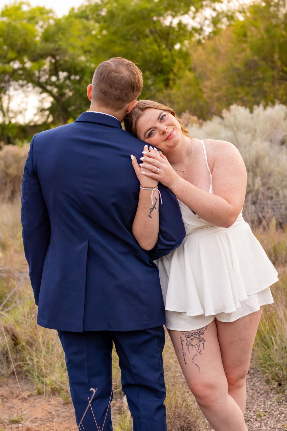 A romantic outdoor portrait of newlyweds sharing an intimate moment in a desert landscape.