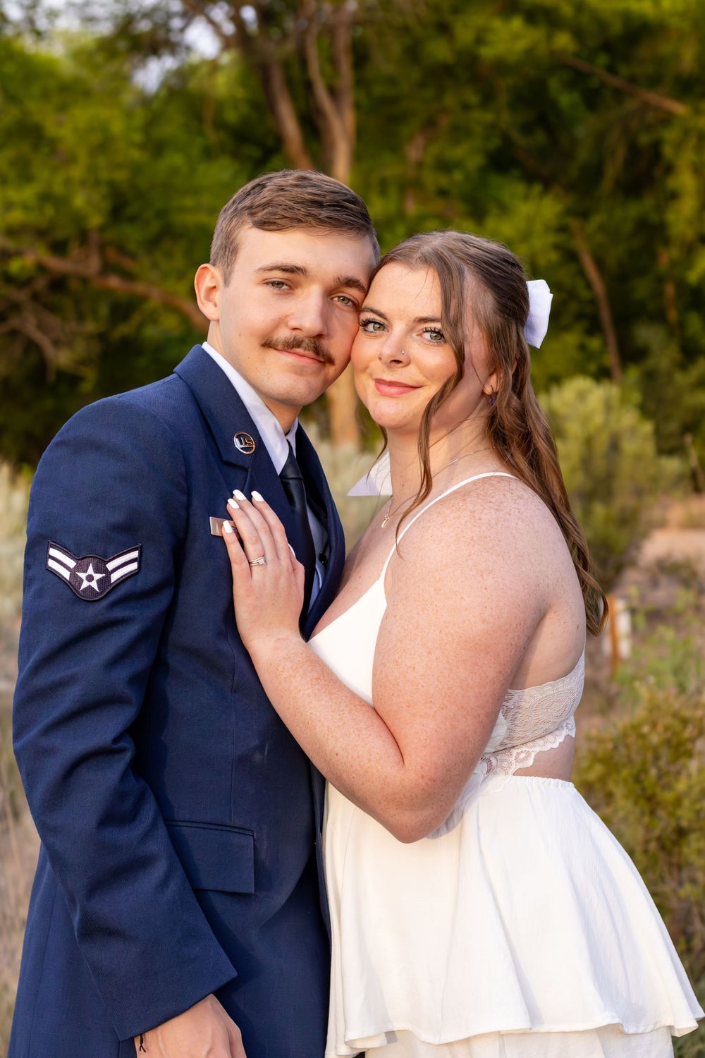 A tender moment between newlyweds at sunset with the groom in Air Force uniform.