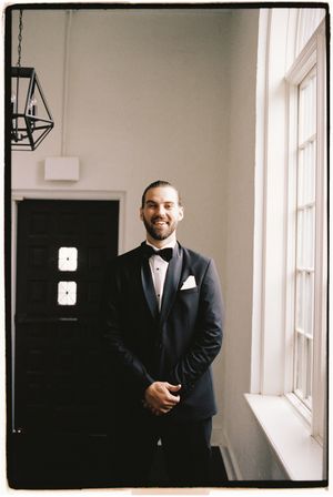 Three candid black and white photos show a person in a dark suit standing by a bright window in an interior hallway.