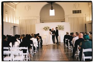 A panoramic view of an elegant white wedding ceremony venue with rows of chairs and decorative floral arrangements.
