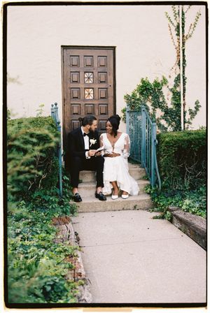 A couple sits together on outdoor steps by a brown door surrounded by greenery in a series of romantic poses.