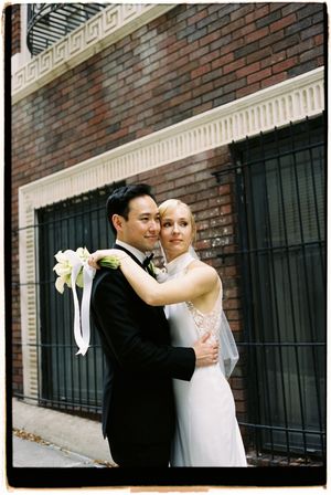 Romantic wedding portraits against a brick wall with black iron fencing in an urban setting.