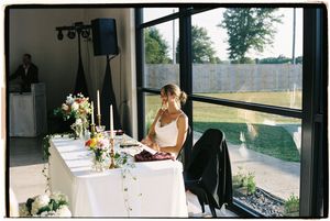 White tablecloths and floral centerpieces line tables in a bright reception venue.