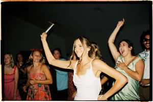 People dancing and celebrating at a lively party with warm lighting and festive atmosphere.