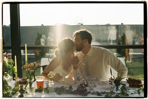 A romantic sunset dinner scene on a balcony with flowers and glassware on the table.