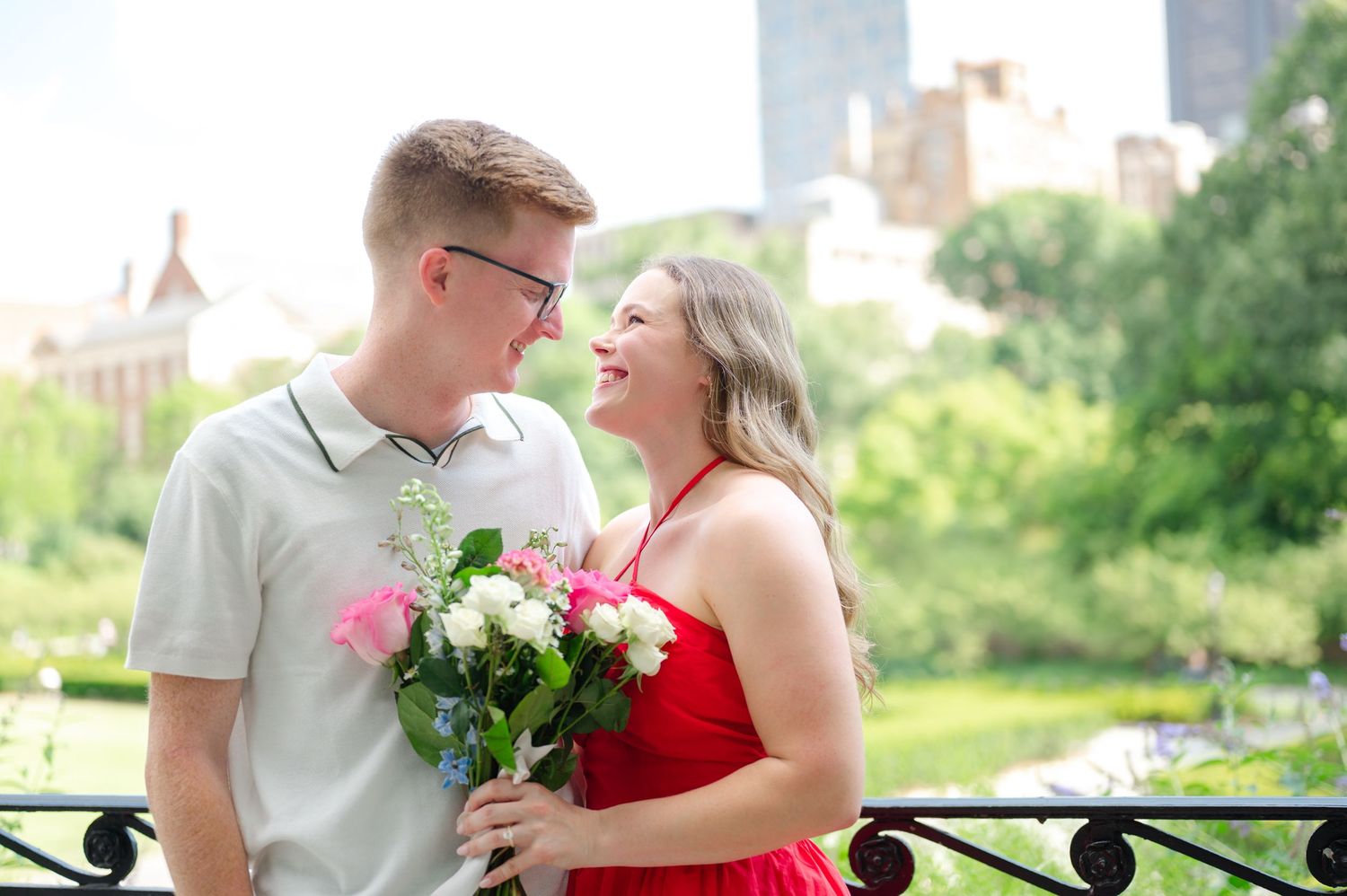 Romantic moment between couple in wedding attire by white fence in rustic outdoor setting.