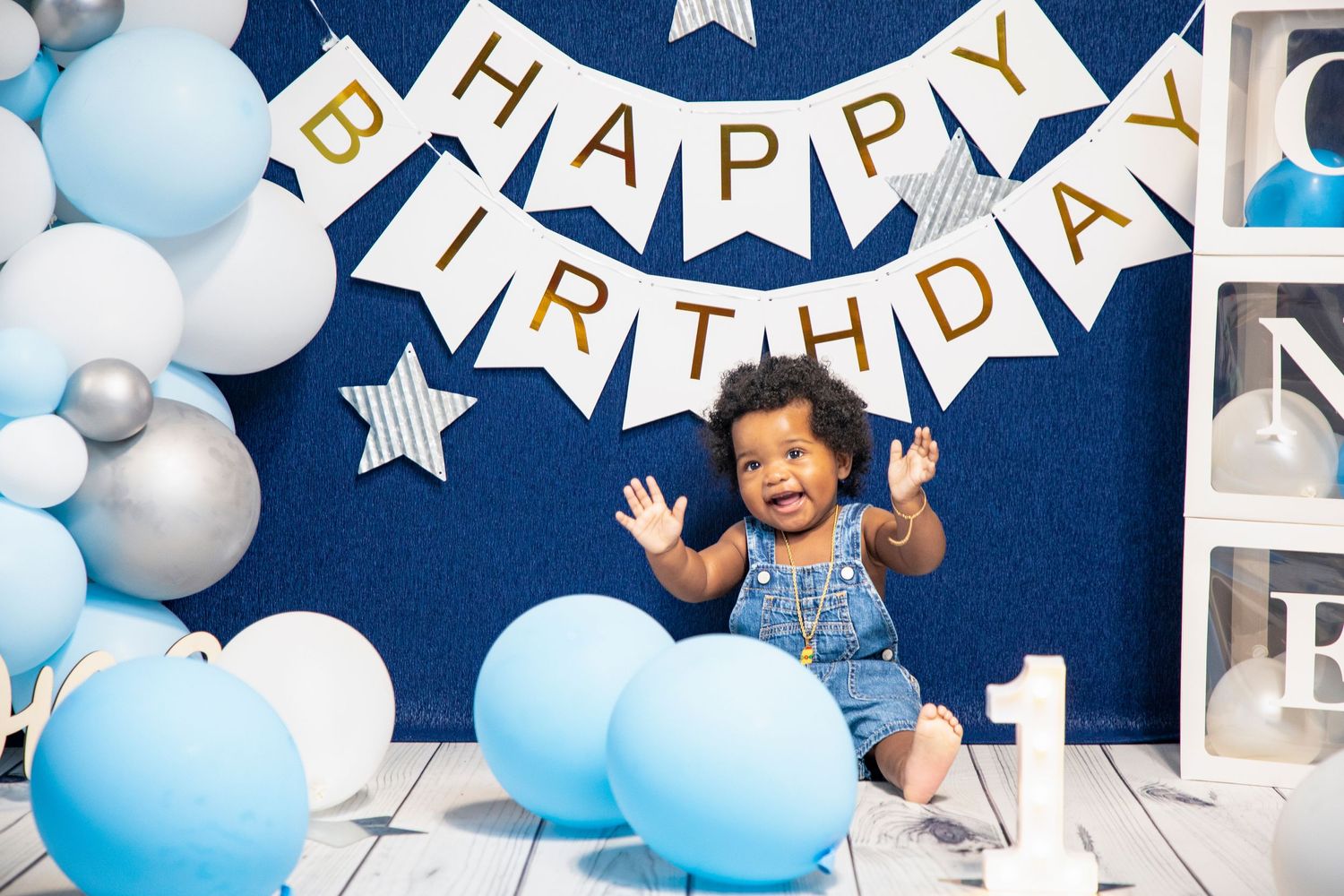 Birthday party setup with blue balloons, white stars and 'Happy Birthday' banner against navy backdrop.