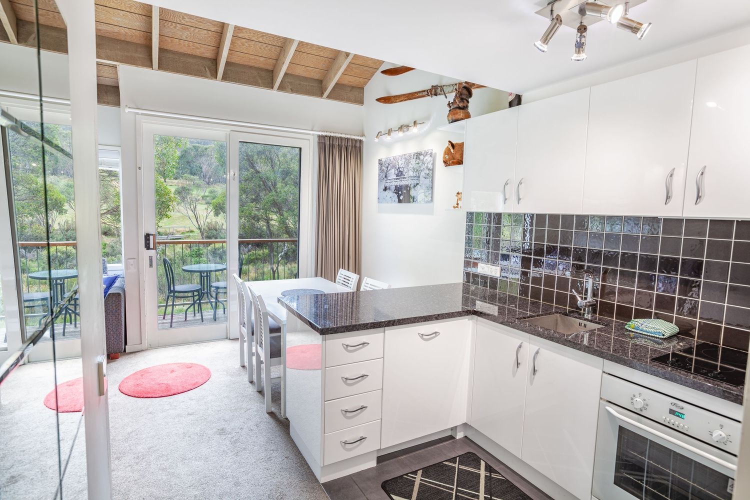 Modern open concept kitchen and dining area with white cabinets and wooden beams in a vacation rental property.