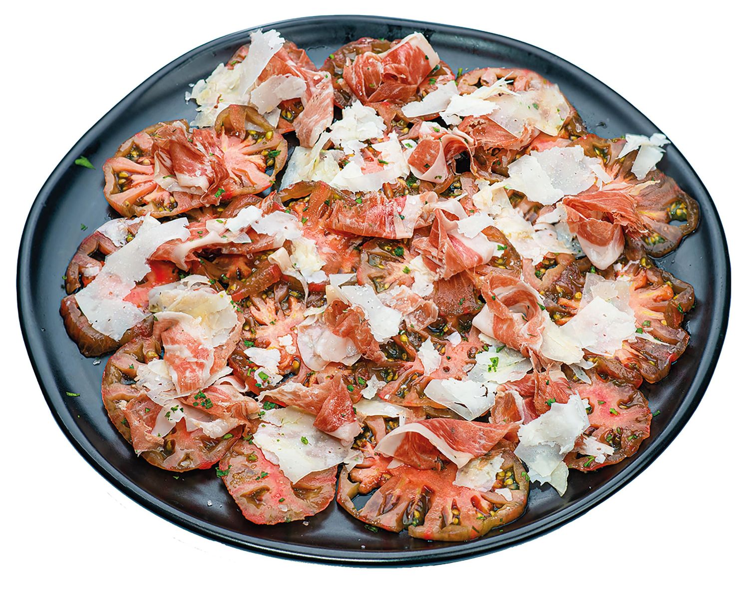 Tomate rojo en rodajas dispuesto en un plato azul con salsa blanca y hierbas frescas.