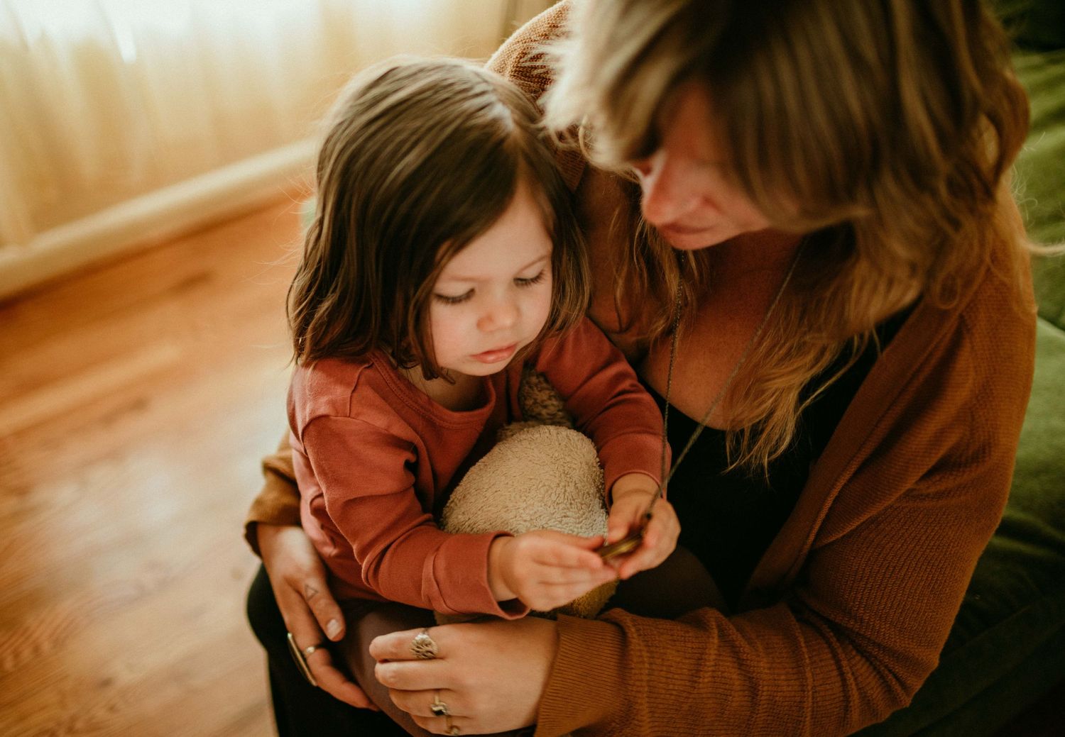 sitting on their lap, child is trying to open mother's locket to show pic inside. portland, oregon family photographer