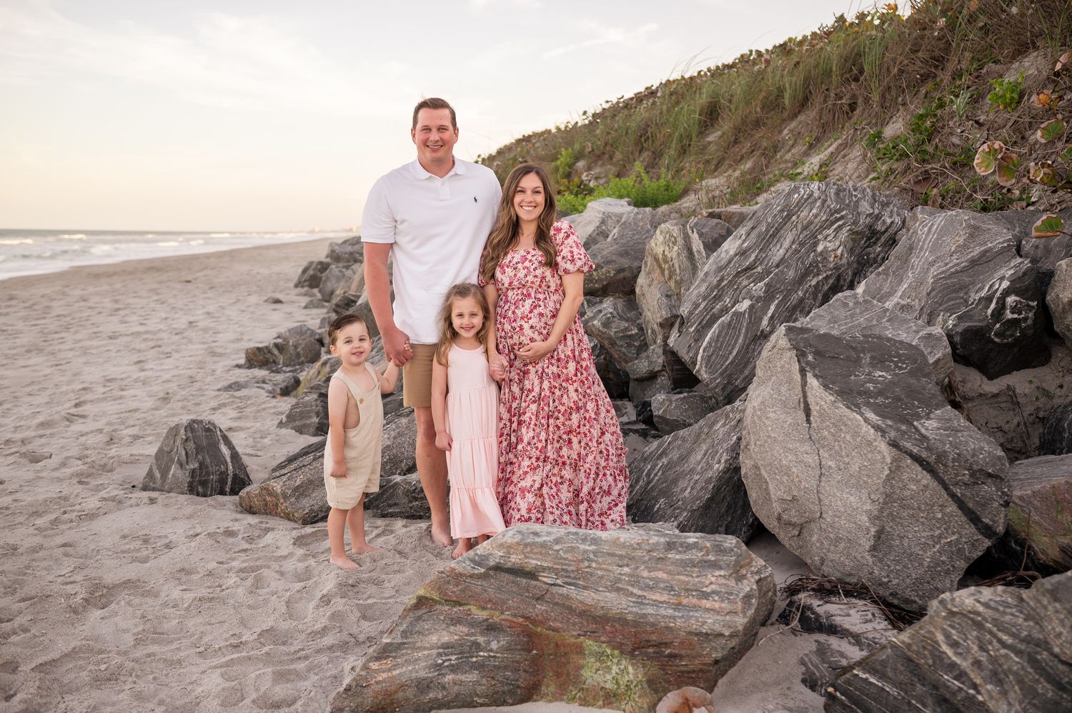 Family standing in front of rocks at beach photoshoot session maternity pregnant Melbourne Cocoa Beach Vero Florida Brevard County