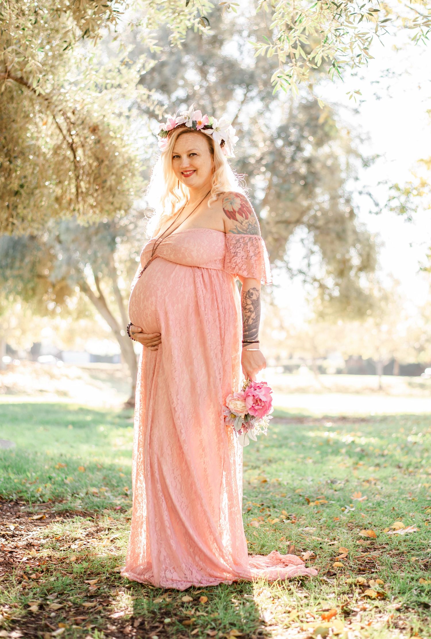 Ethereal maternity portraits in a park setting with golden sunlight and fall leaves.