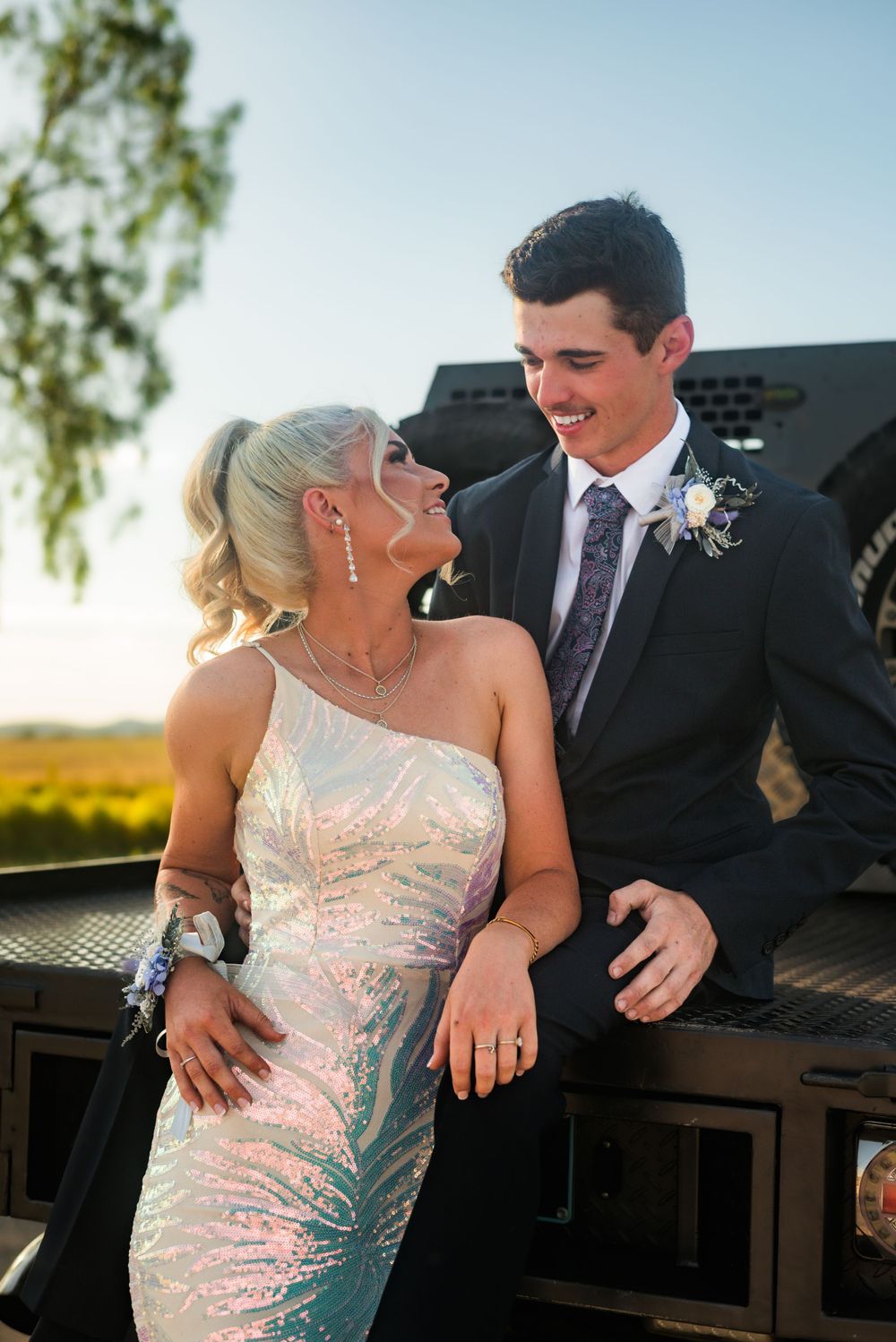 Formal couple sharing intimate moment at outdoor venue during sunset.