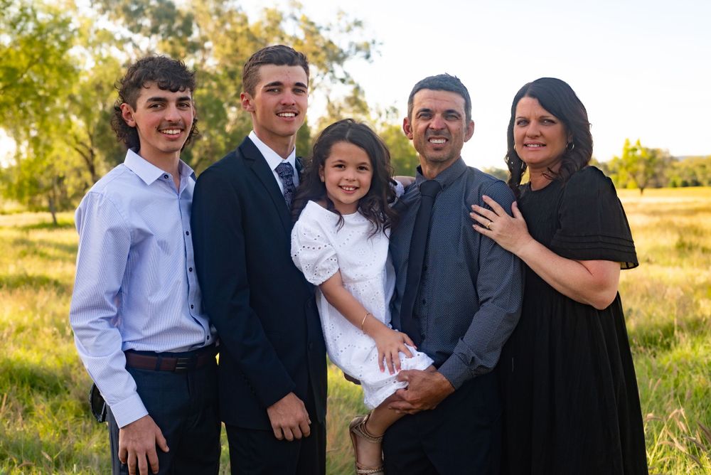 Family group photo outdoors with scenic golden field background.