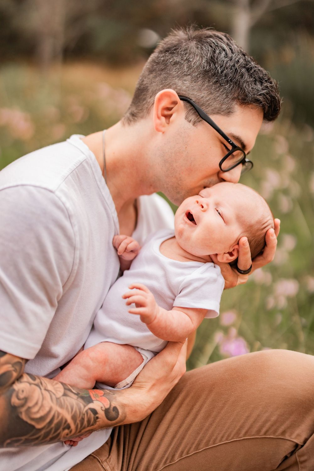 Intimate parenting moment captured in soft natural lighting outdoors.