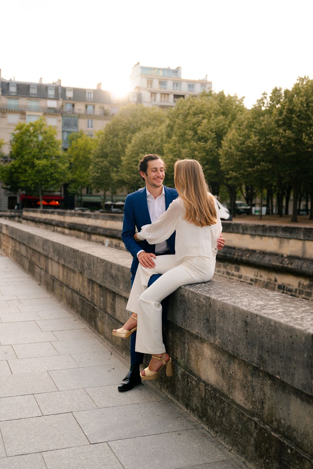 A couple enjoys a romantic moment sitting along the Seine River in Paris at sunset.