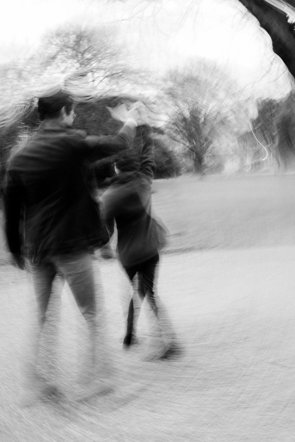 Black and white motion blur photograph of people walking in a snowy winter landscape.