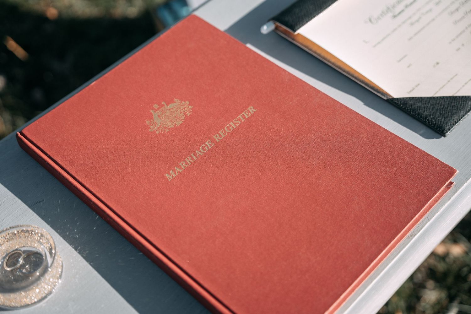 Red marriage license book with documents on dark surface.