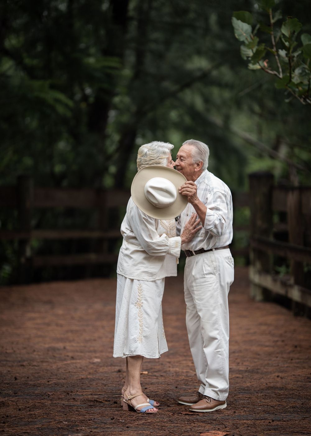 A loving couple shares an intimate moment on a forest path.