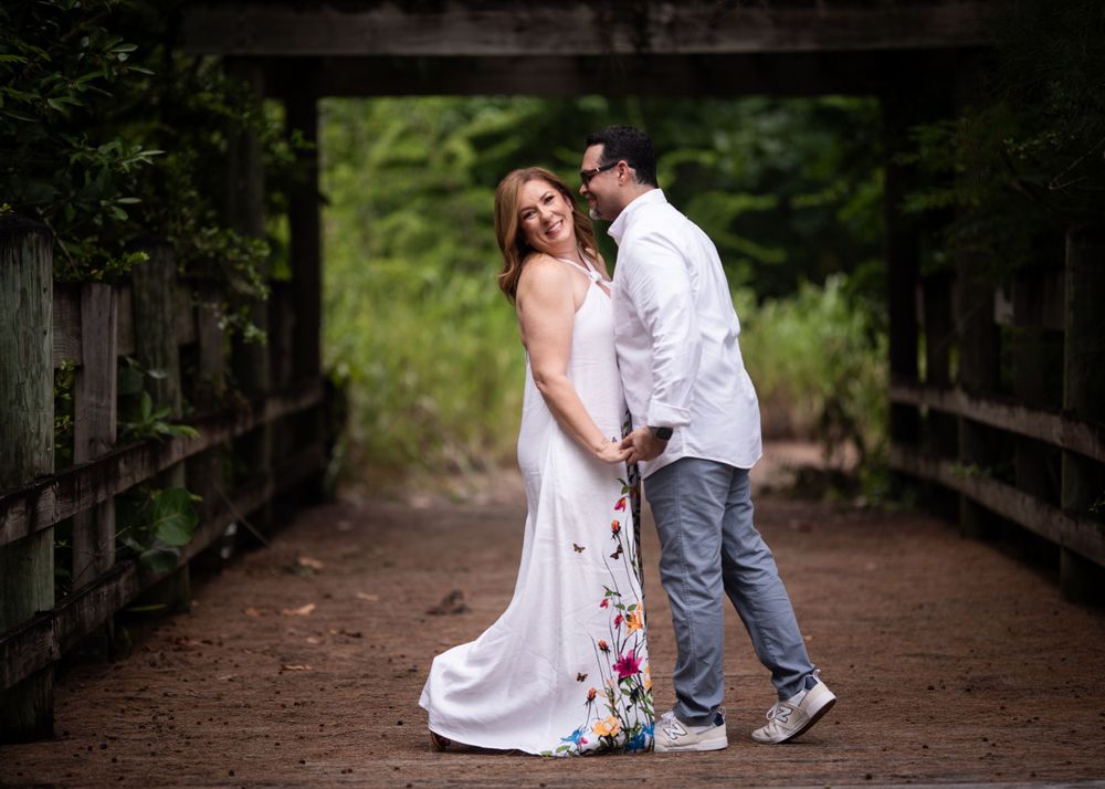 A couple shares a romantic moment on a wooden bridge in their wedding attire.