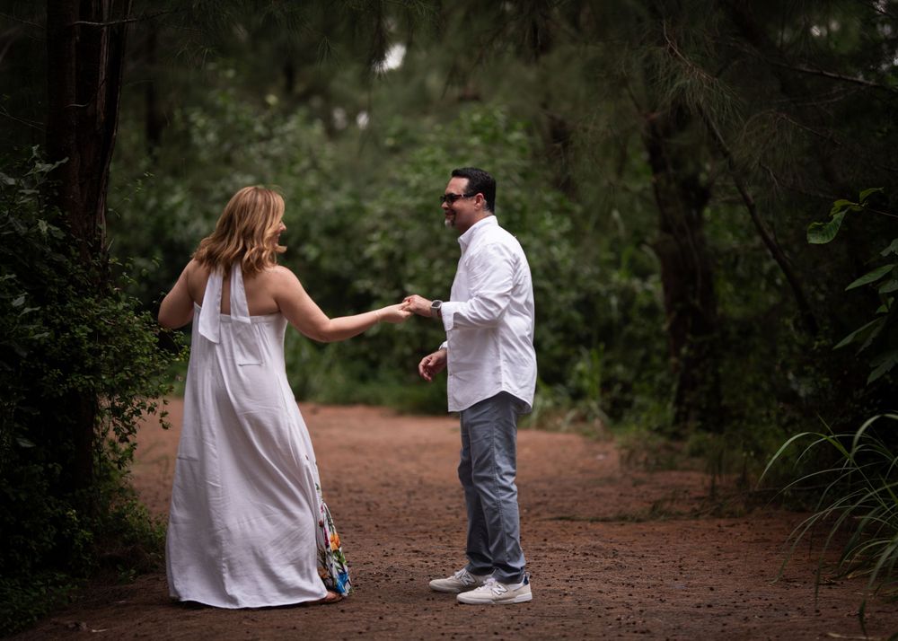 A couple dances together on a dirt path surrounded by lush greenery.