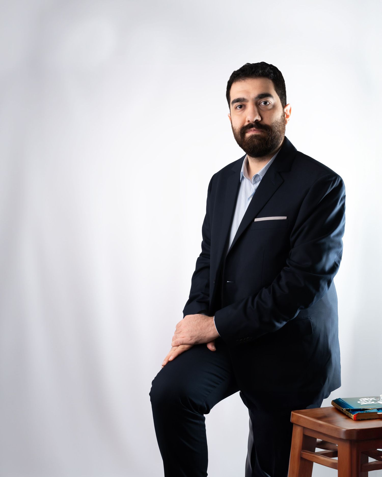Professional studio portrait in navy suit against white background.