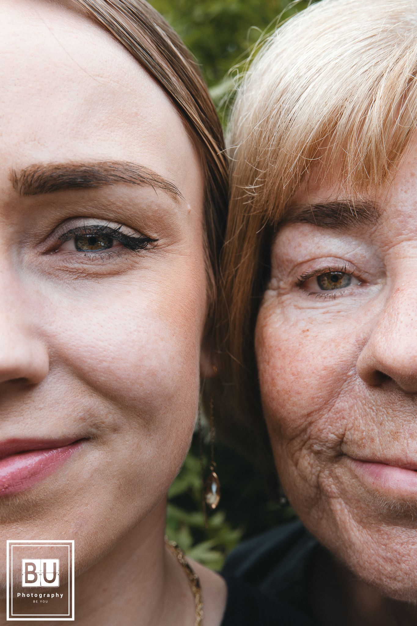 A close-up portrait of two people smiling at the camera with a blurred green background.

- BU Photography -