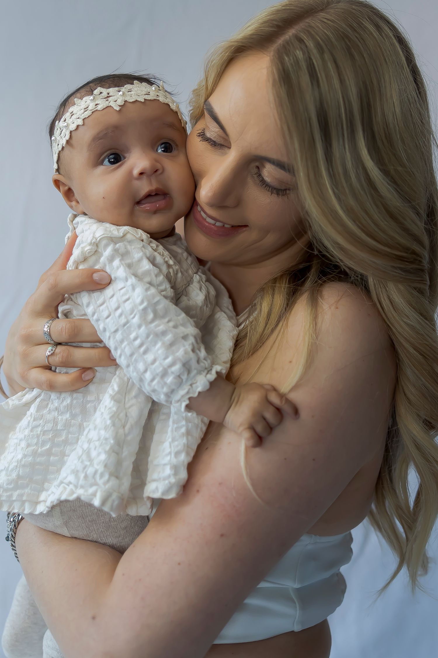 A tender moment between parent and baby both dressed in white.