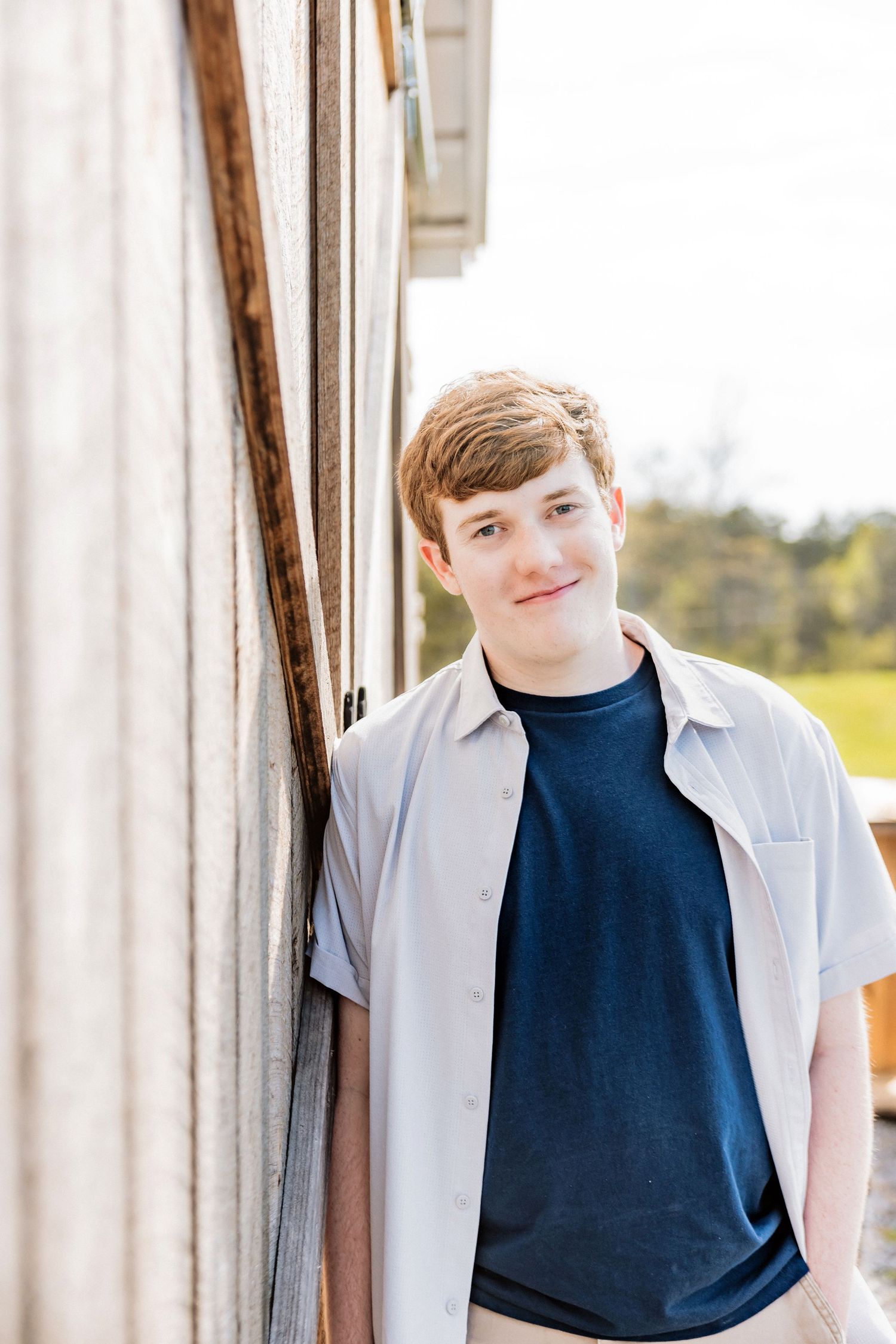 Young person in casual outfit leaning against white wall outdoors.