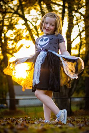 Cute young girl posing in Halloween dress during golden hour in the fall. Portrait taken by Chris Suits Photography