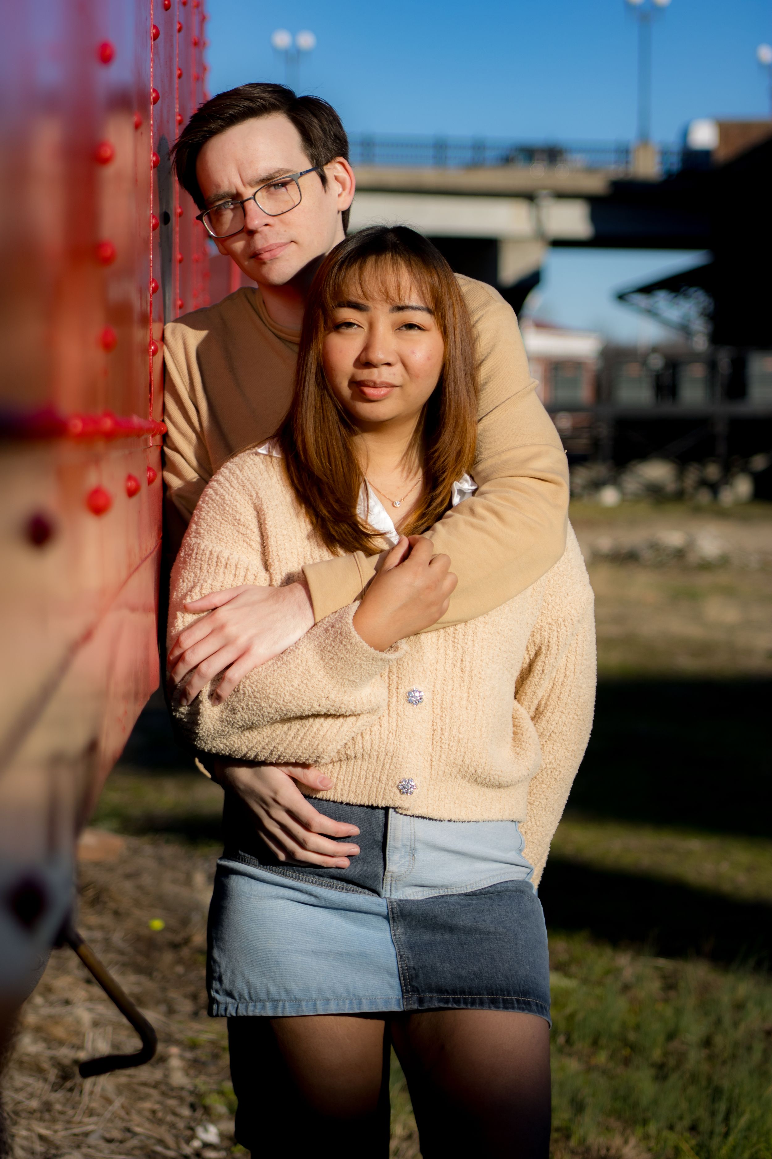 Couples posing next to a red train car in Old Town Petersburg Virginia, portrait taken by Chris Suits Photography