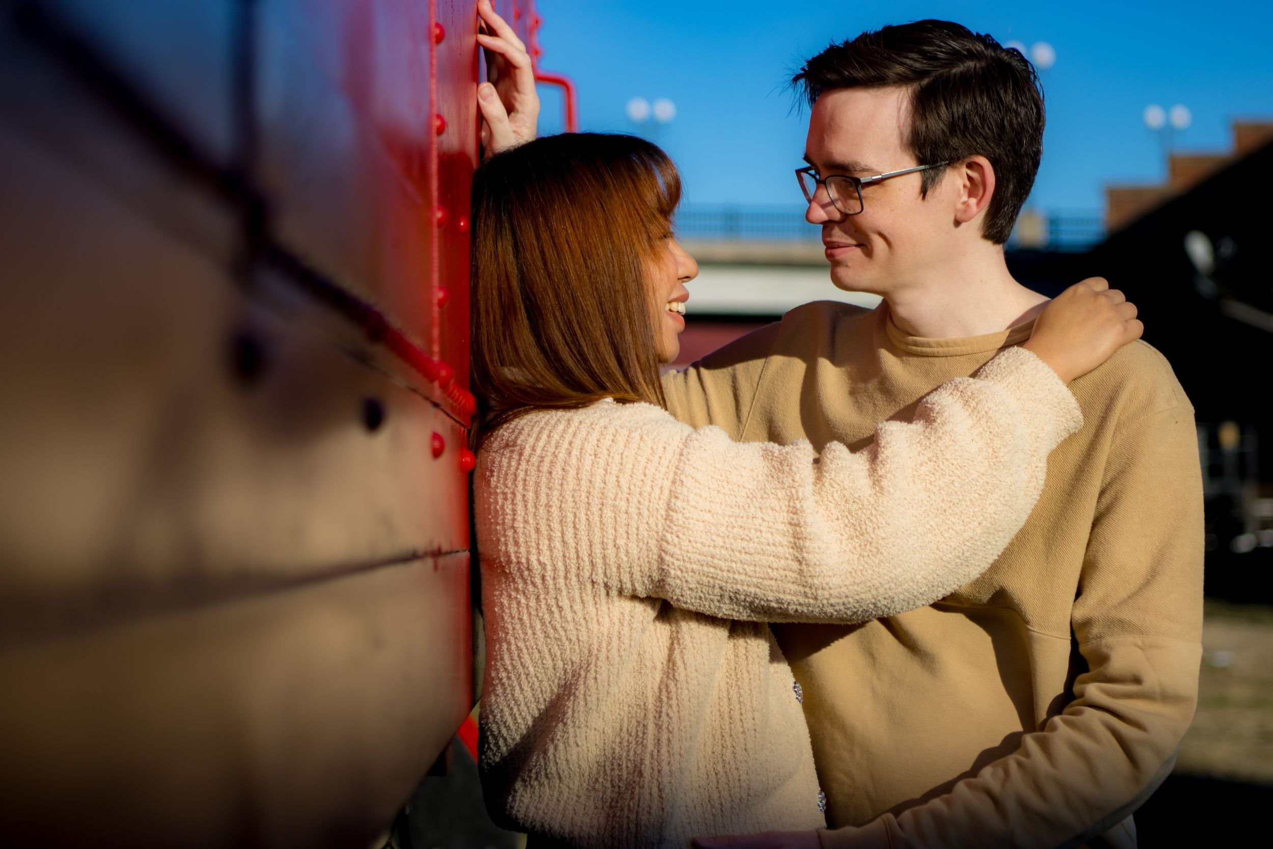 Couples posing next to a red train car in Old Town Petersburg Virginia, portrait taken by Chris Suits Photography