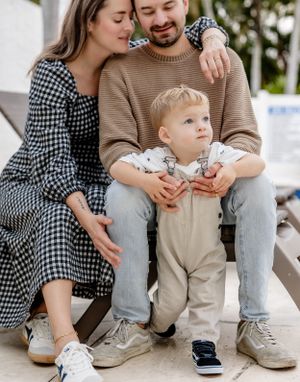 A casual family photo on outdoor steps with coordinating checkered and knit outfits.