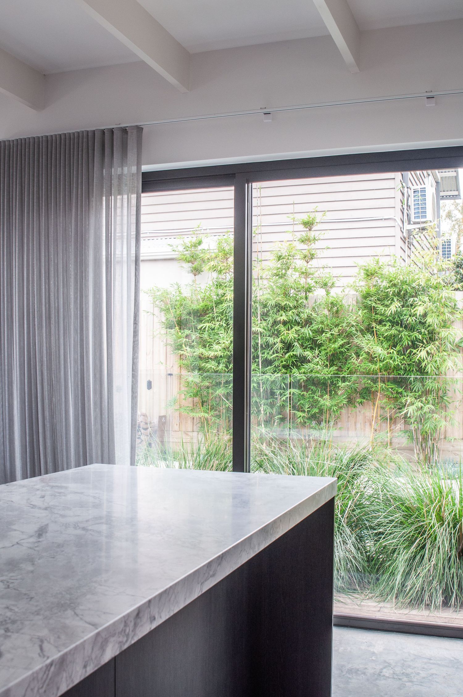 Marble kitchen island with large window overlooking bamboo garden.