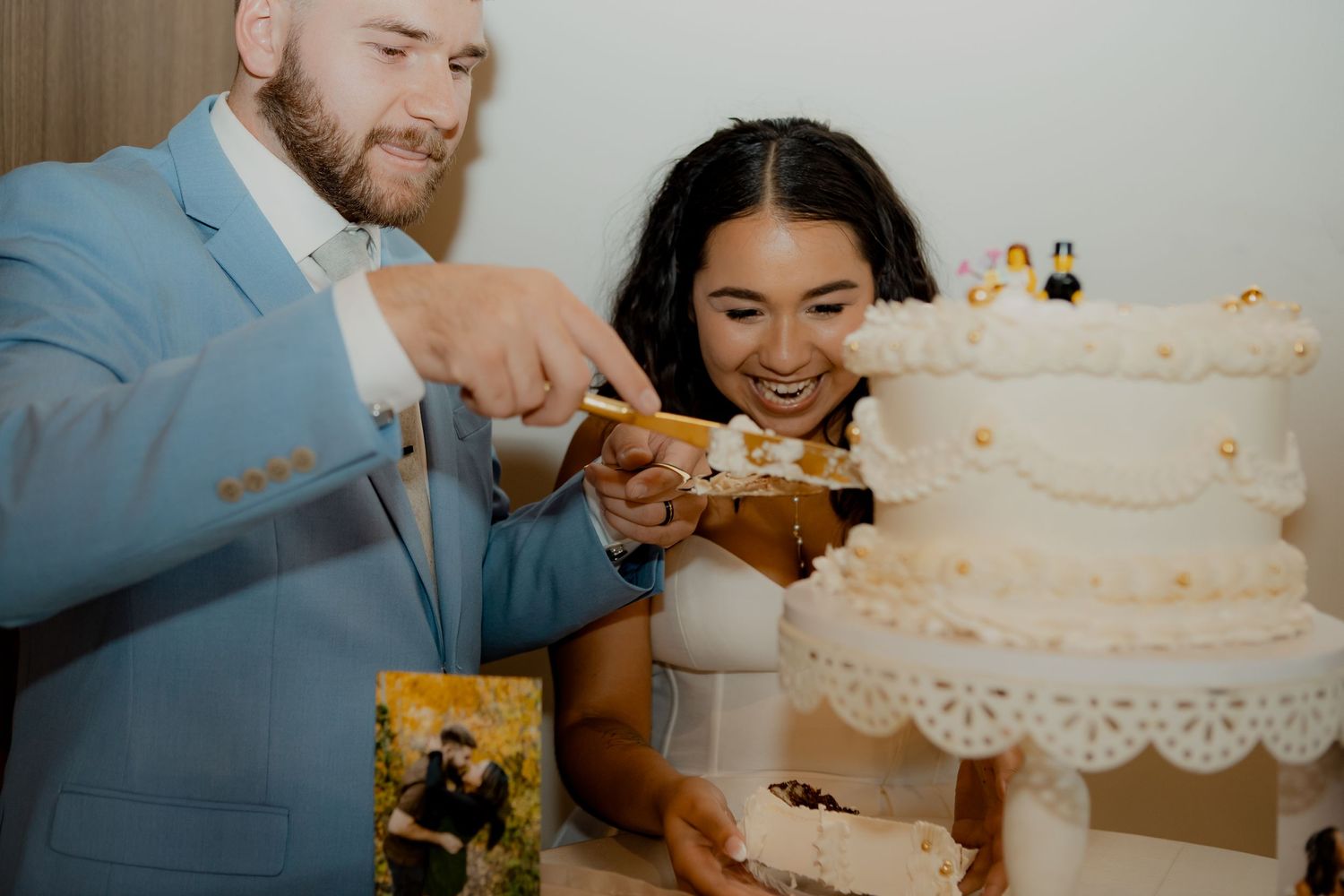 Newlyweds cutting their white tiered wedding cake together at the reception.