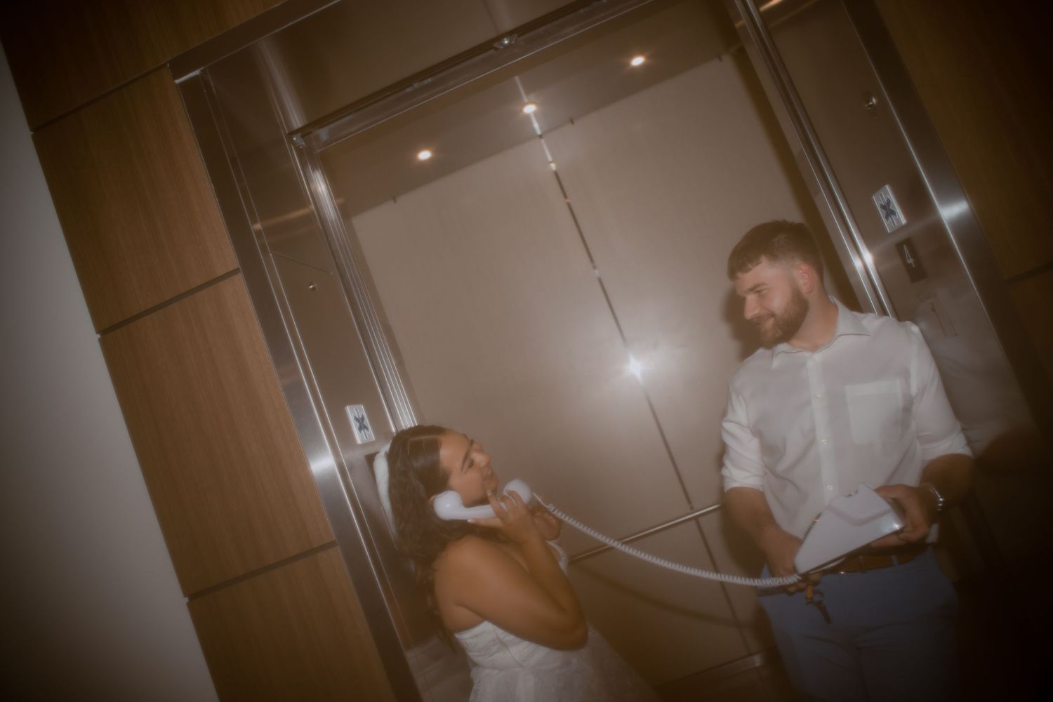 A candid moment between two people in white attire in an elevator.