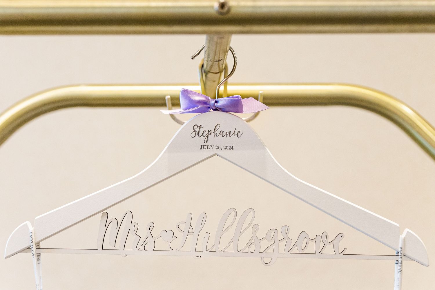 White wedding dress hanger with purple bow and personalized name.